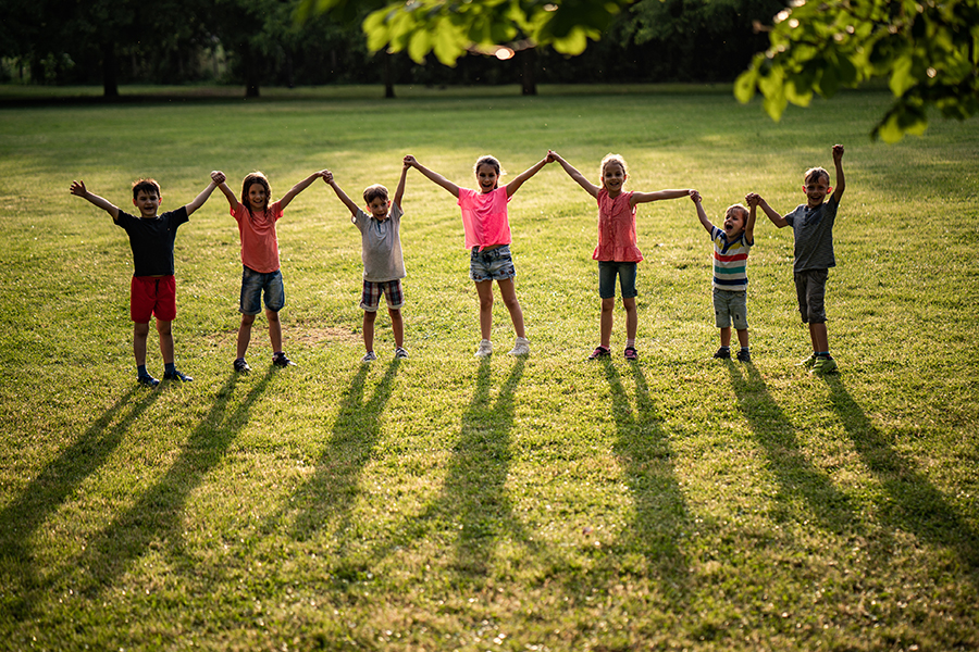 Group of happy children standing and holding hands in park